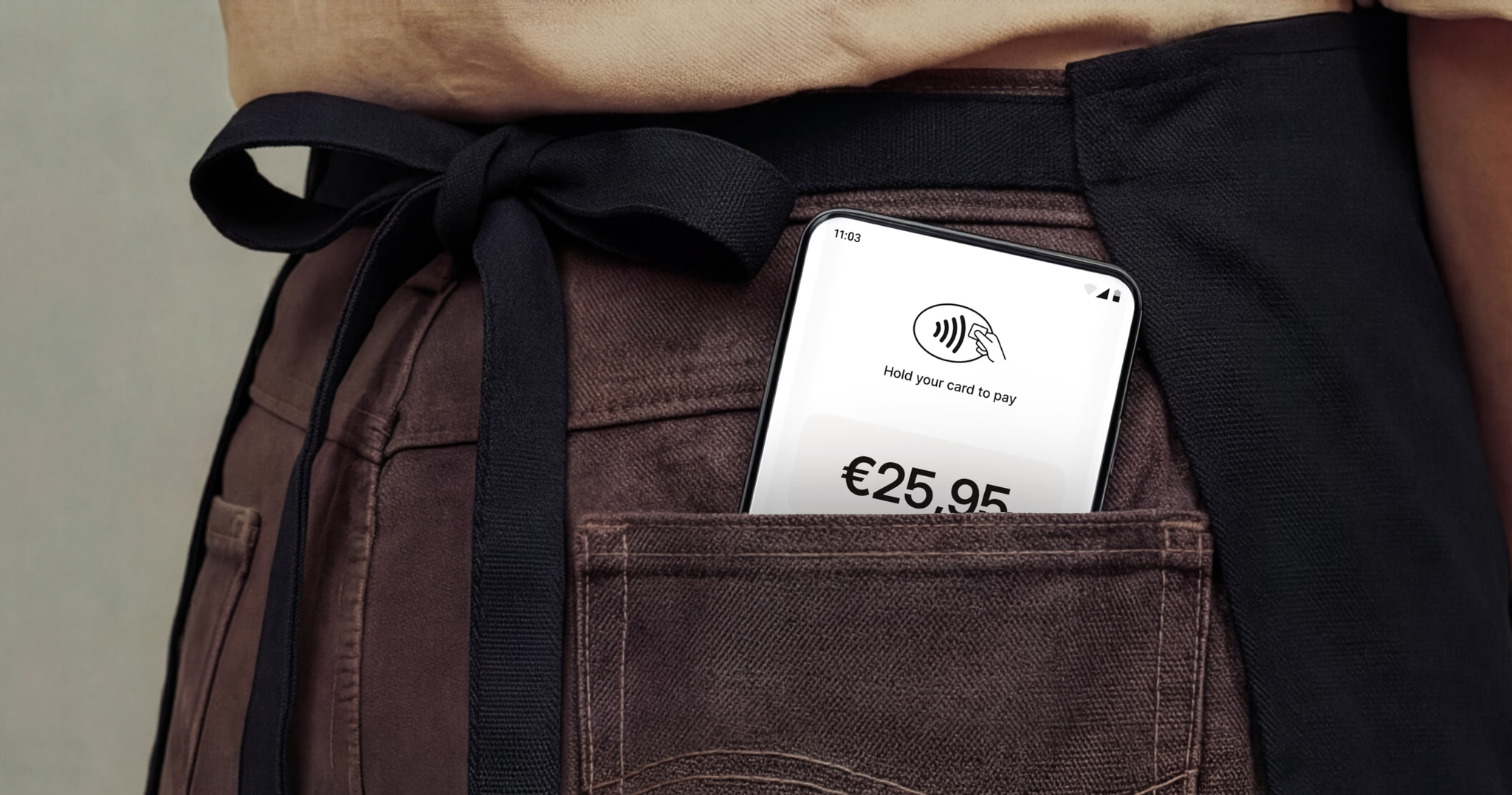Smartphone in an apron pocket showing a contactless payment screen.