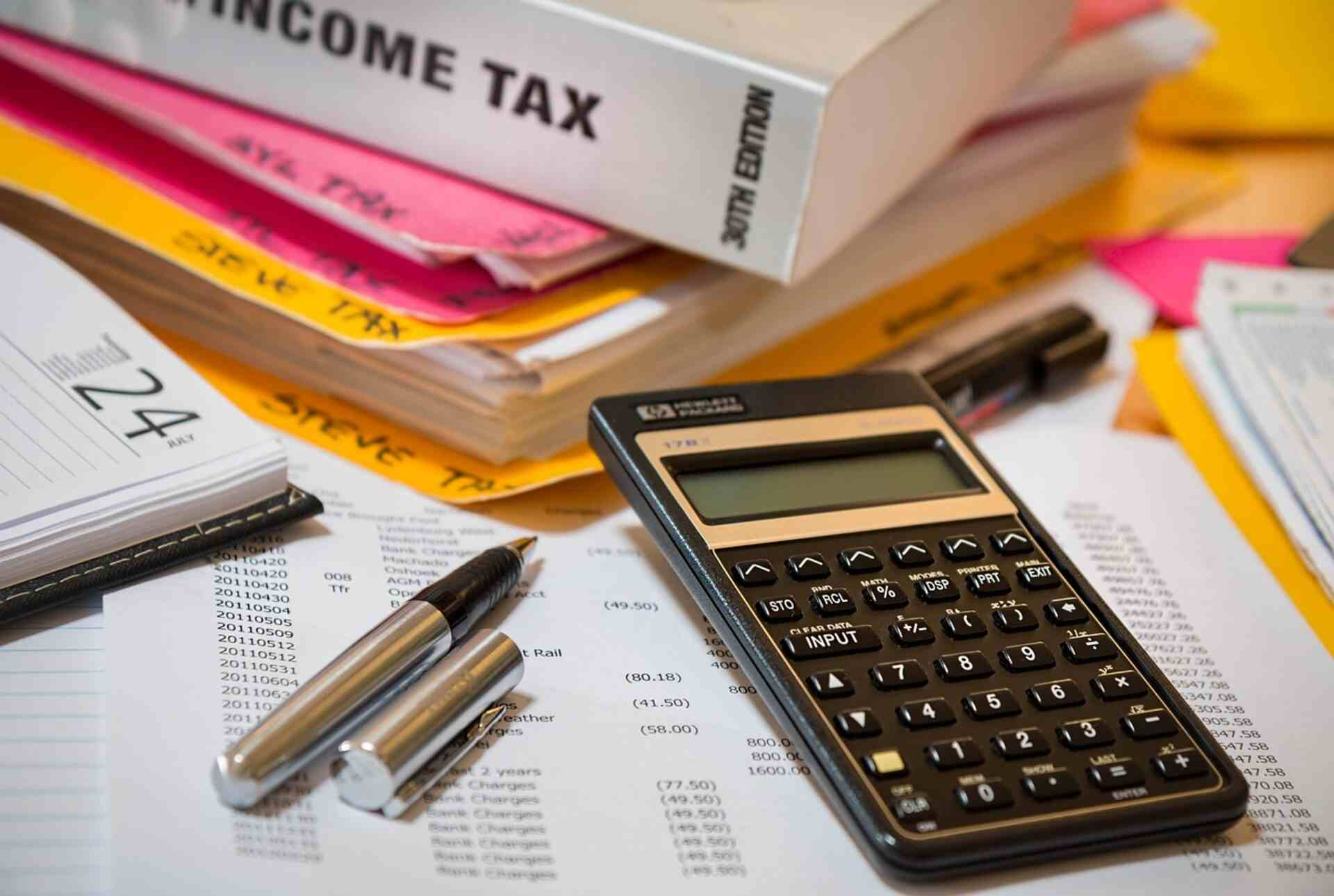 Calculator, pens and income tax paperwork spread across a desk.