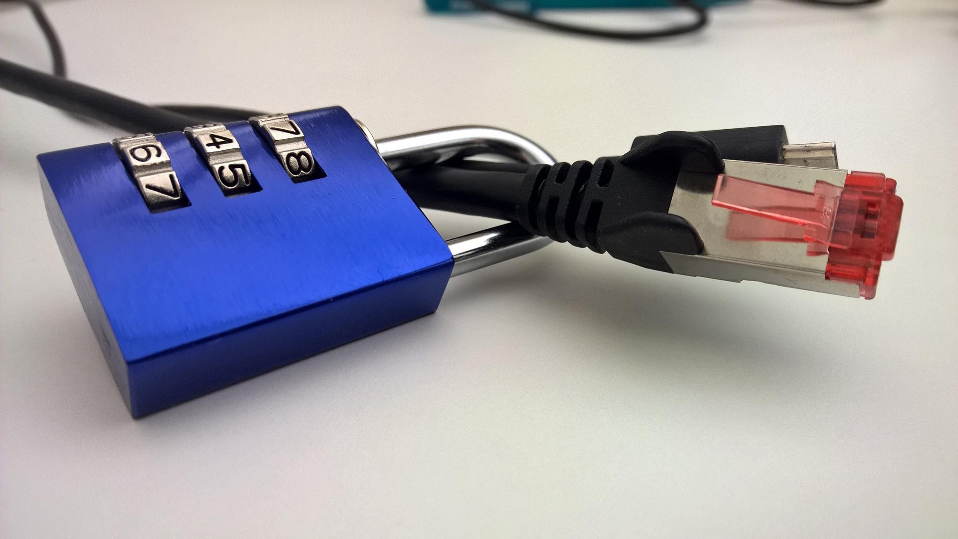 Blue combination padlock securing an Ethernet network cable.